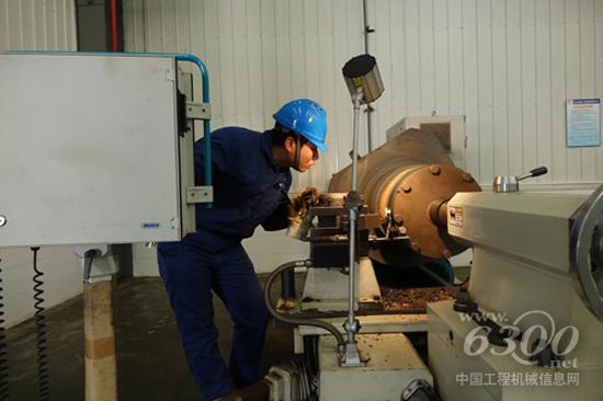 图为机加工人精准测量大吨位矿用车加工件