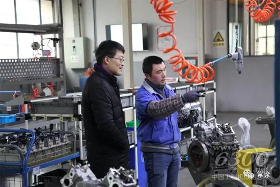 张新总经理（左）在河海路基地向员工了解轻型发动机装配情况